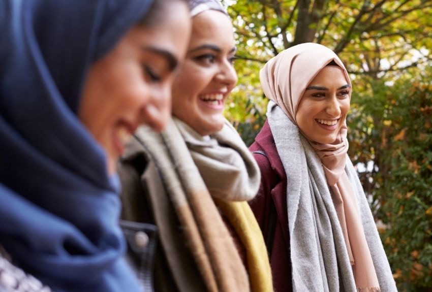 Three women wearing hijab smiling and talking