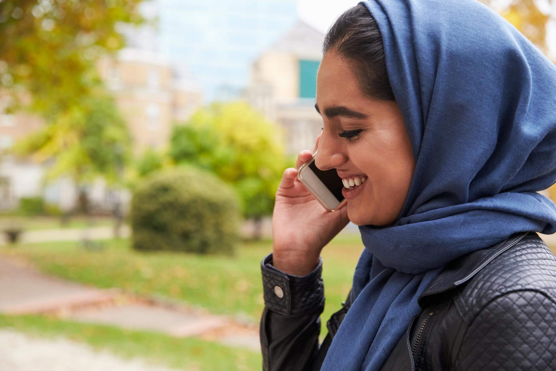 Woman in headscarf smiling while talking on the phone