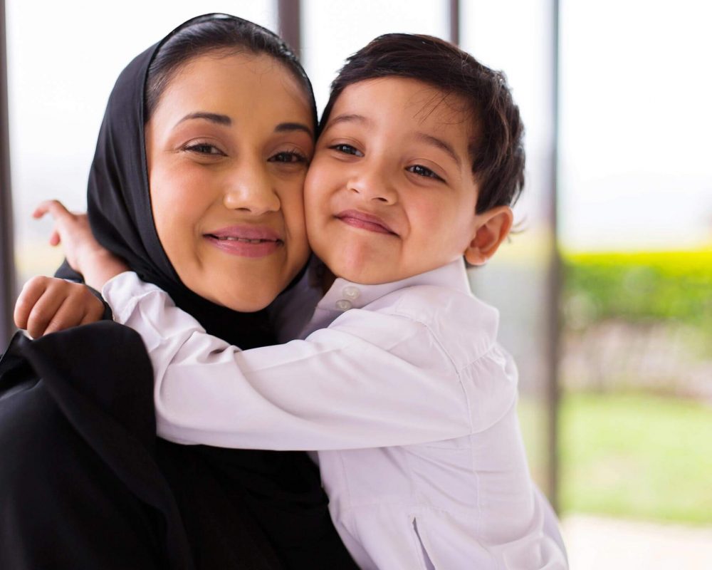 Woman weating hijab smiling and hugging her son